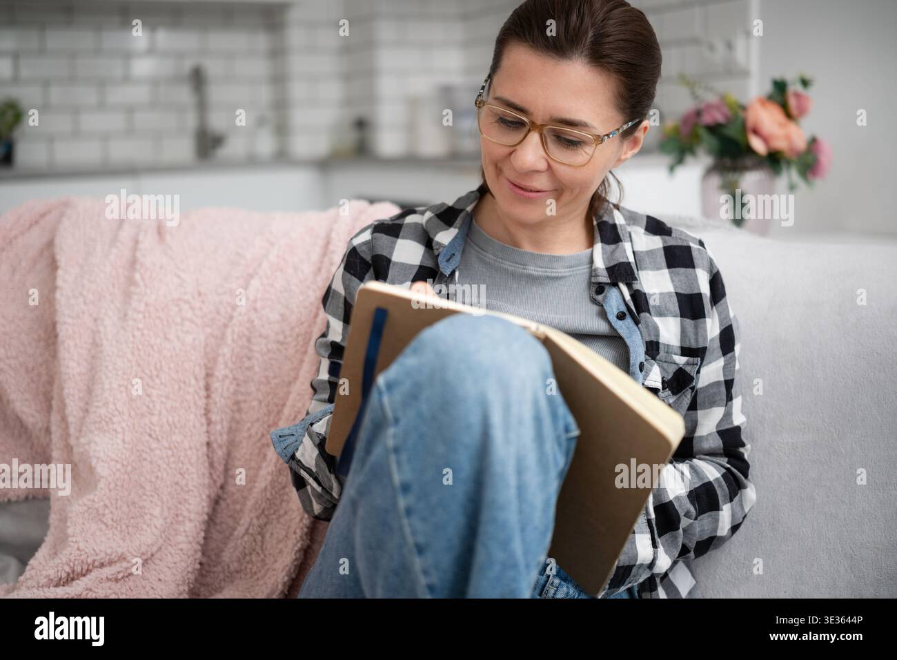 Una ragazza con occhiali che scrive note in Un notebook fa Un elenco di cose importanti da fare a casa Foto Stock