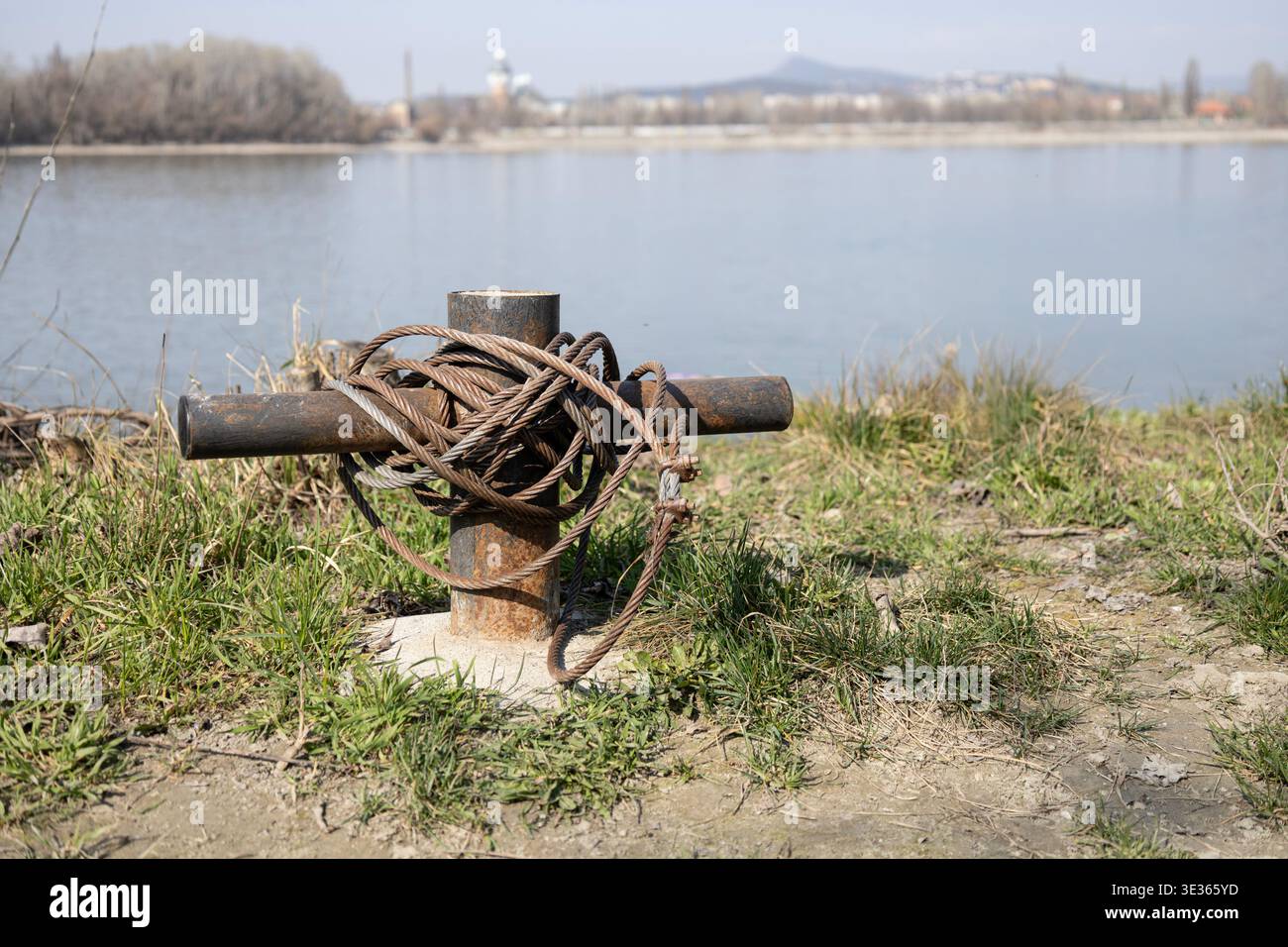 Vecchio dissuasore in metallo arrugginito con spesso cavo in acciaio sul lungofiume Foto Stock