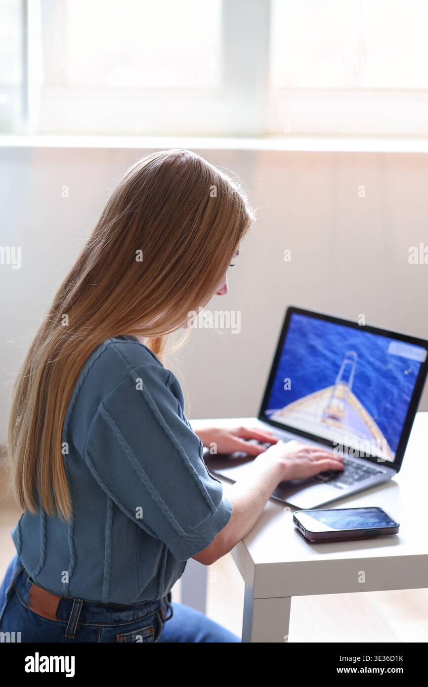 Donna che lavora su un notebook a casa, che naviga sul sito Web di viaggi con vista sull'oceano sullo schermo. Concetto di prenotazione online. Foto Stock