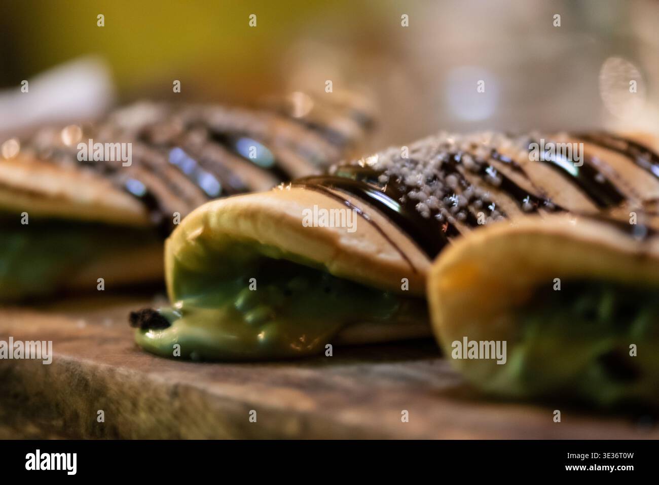 Primo piano di frittelle con crema di pistacchio e guarnizione al cioccolato. Foto Stock