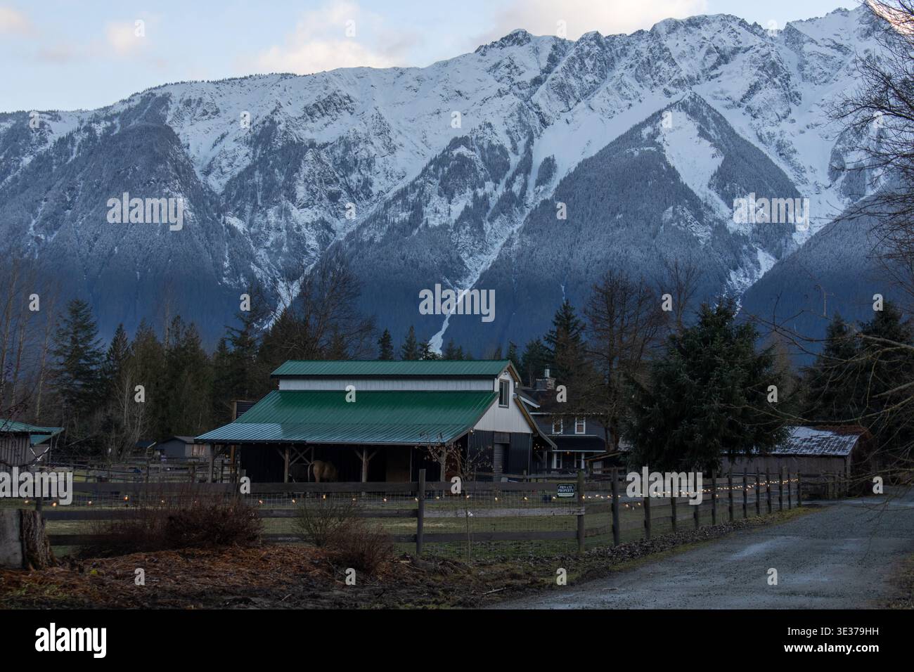 Fienile rustico con tetto verde e luci a corda alla base delle montagne innevate a Pemberton, British Columbia, Canada Foto Stock