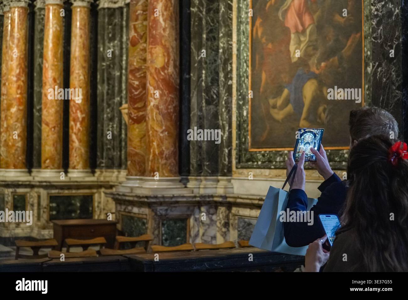 Santa Maria del popolo. Turisti che fotografano opere d'arte di Caravaggio vicino a colonne in marmo riccamente venate all'interno della storica chiesa di Roma, in Italia. Foto Stock