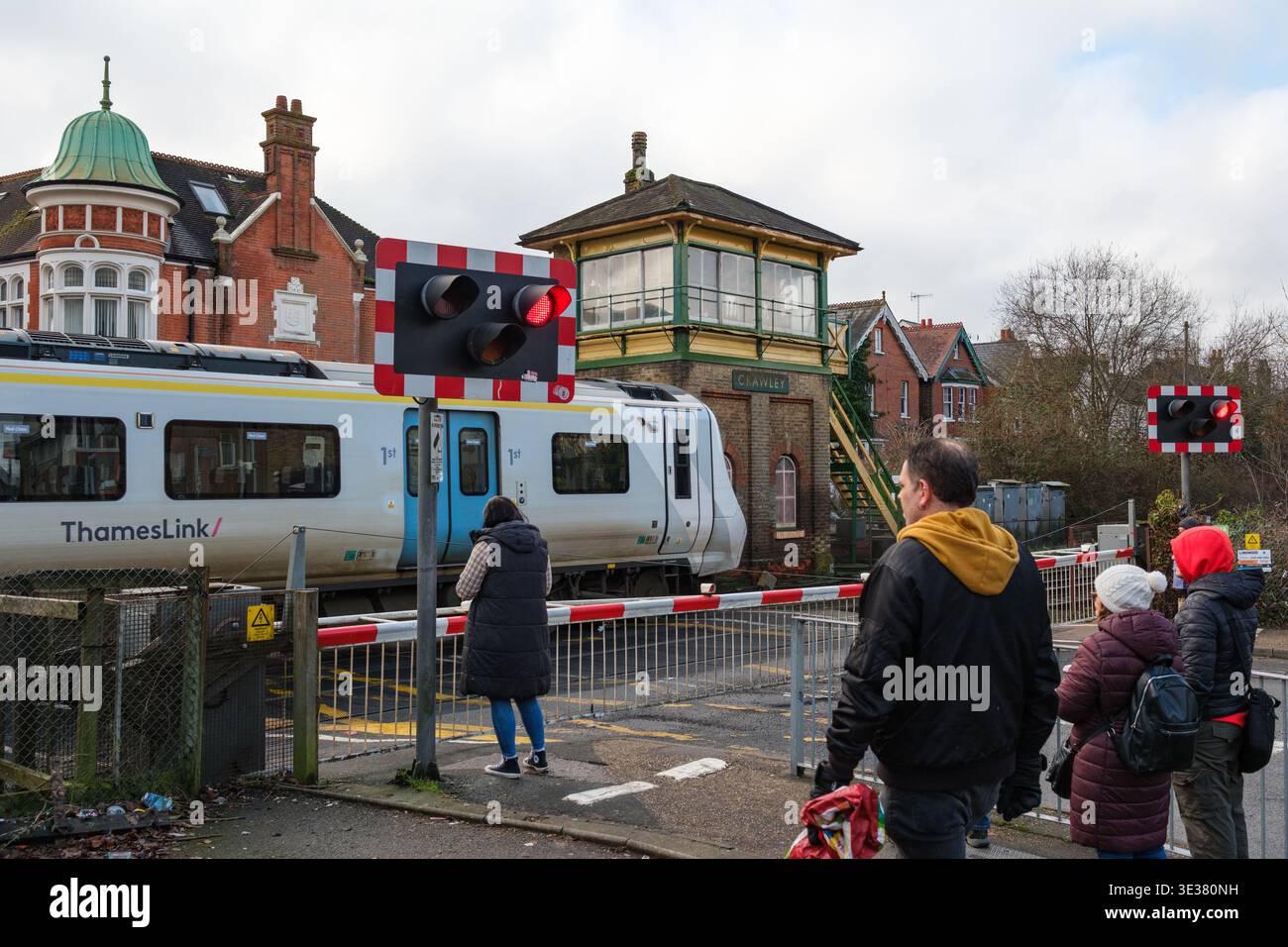 La gente aspetta al passaggio a livello della ferrovia a Crawley Brighton Road, sede della segnaletica vittoriana classificata di secondo livello, mentre passa un treno del Tamigi. Foto Stock