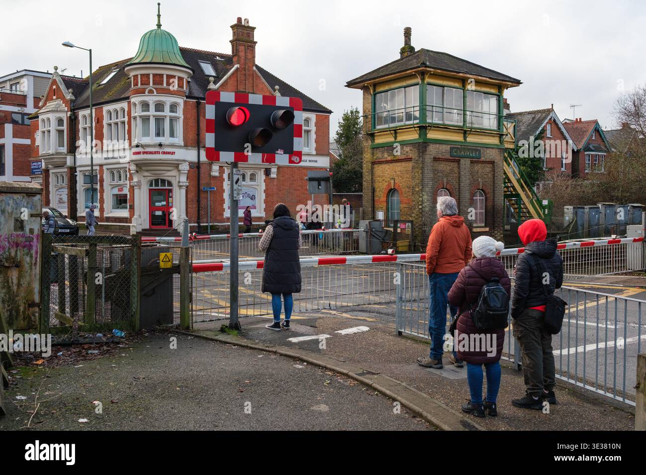 La gente aspetta al passaggio a livello della ferrovia a Crawley Brighton Road, sede della segnaletica vittoriana classificata di secondo livello, mentre passa un treno del Tamigi. Foto Stock