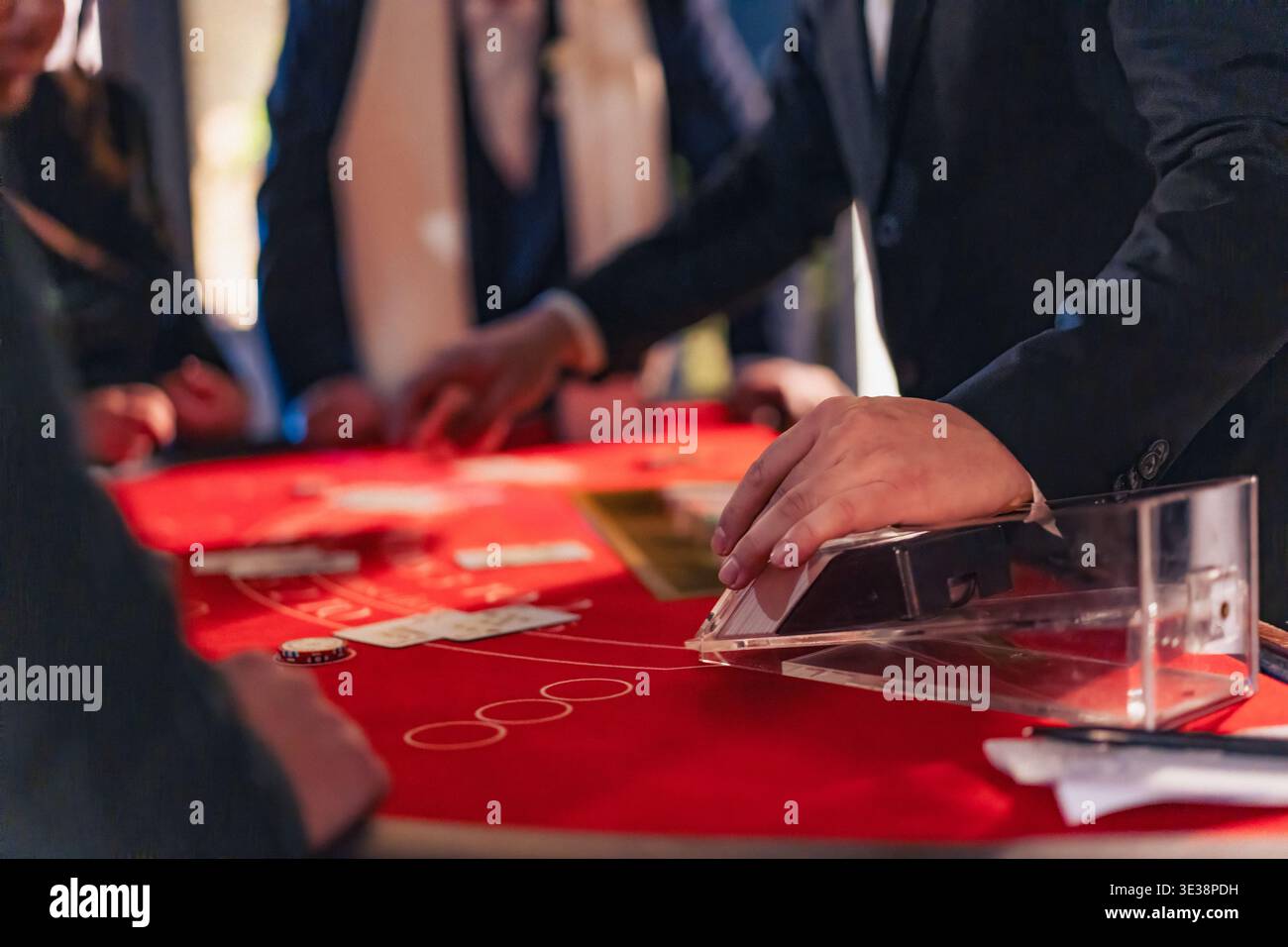 Il mazziere del casinò spara carte sul tavolo del blackjack con i giocatori in giro. Concetto di gioco d'azzardo, rischio e scommesse. Foto Stock