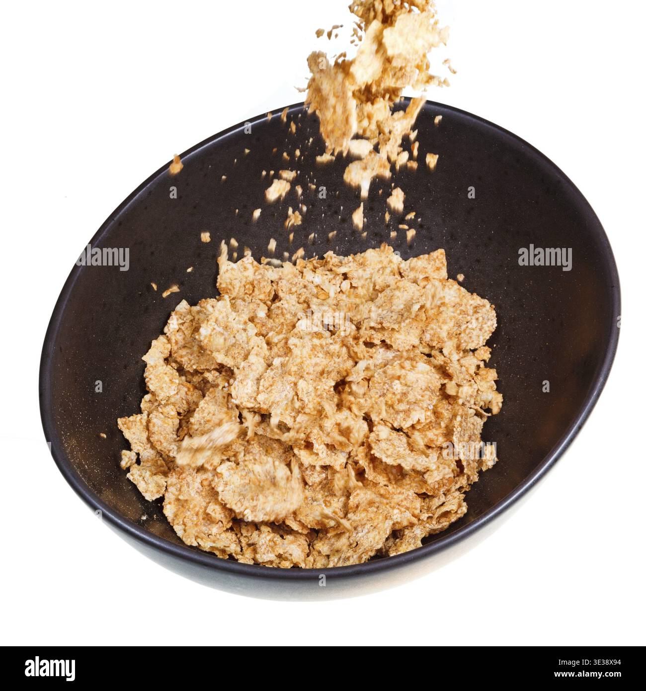 Cereali spolverati in una ciotola scura isolata su sfondo bianco Foto Stock