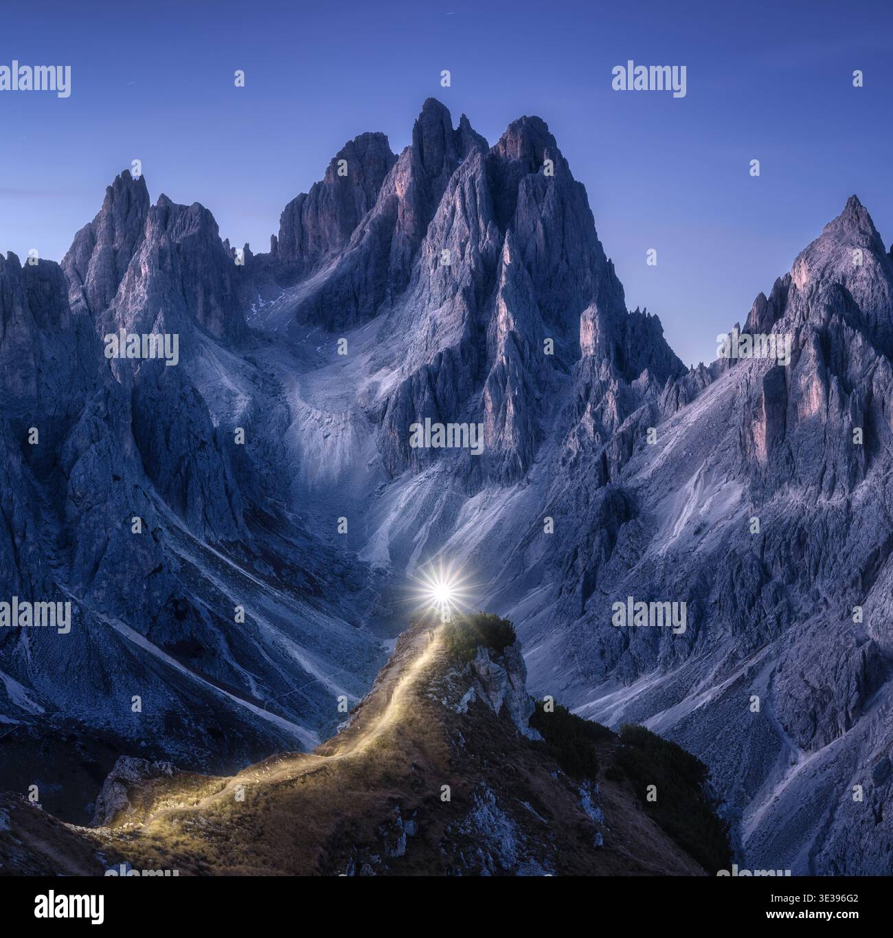 Sentieri di torcia sul sentiero di montagna contro alte rocce di notte Foto Stock