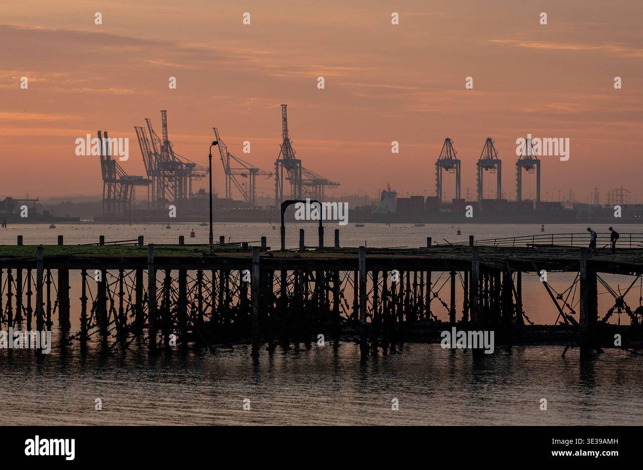 Tramonto sulle gru e sulle navi presso le banchine di Southampton, porto di Southampton, Hampshire, Inghilterra, Regno Unito Foto Stock