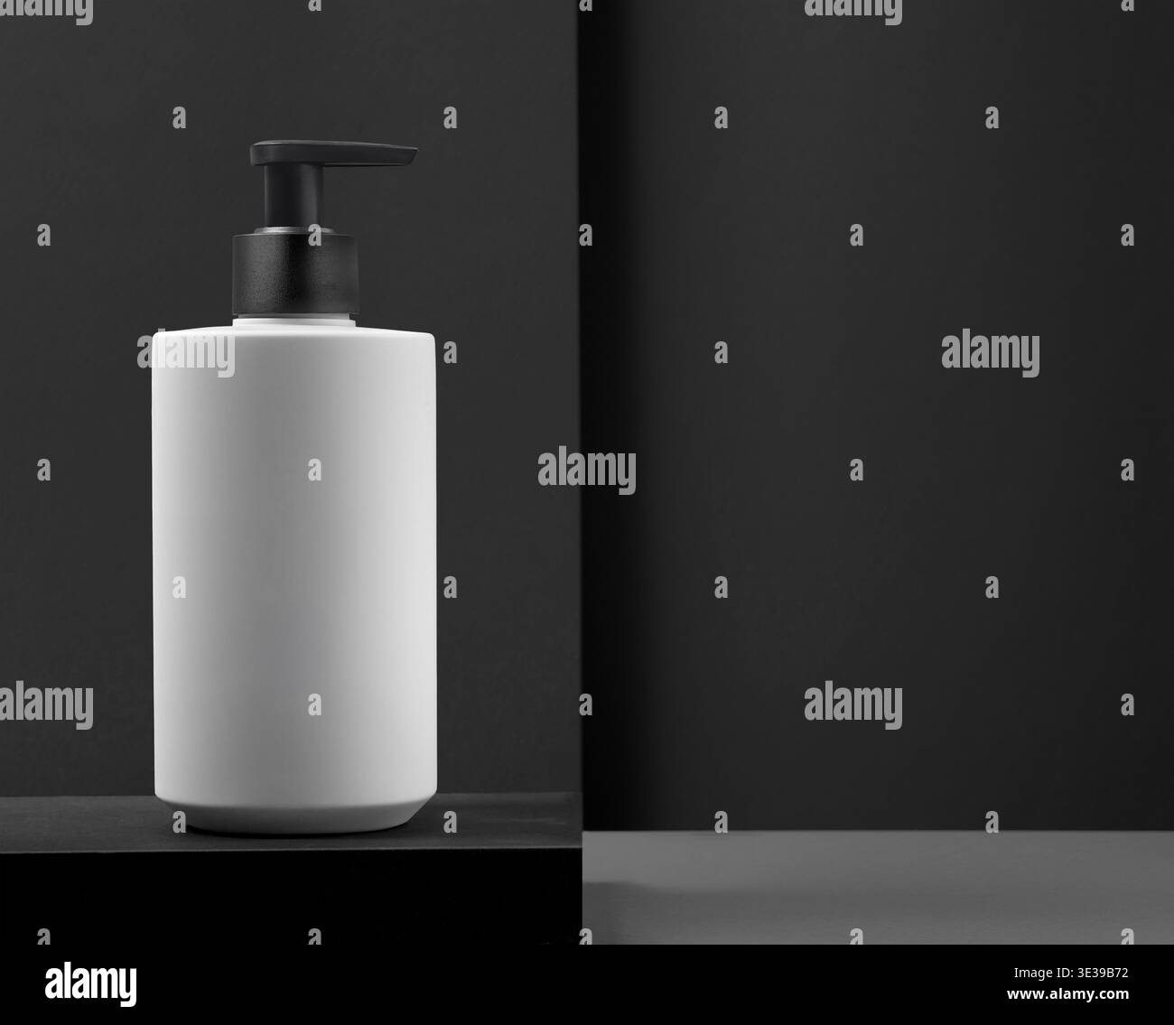 L'elegante biberon bianco per sapone, shampoo e gel doccia con eleganti dettagli neri sullo sfondo nero è perfetto per valorizzare le case moderne e il loro aes Foto Stock