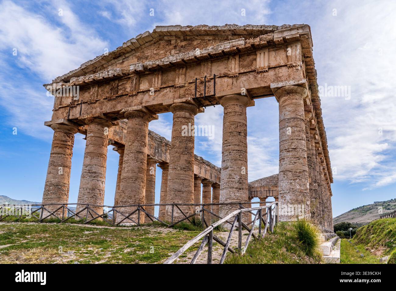 Foto dinamica del Tempio di Segesta che mostra l'allineamento delle colonne doriche e del frontone. L'antica struttura sorge in cima ad una collina erbosa recintata, un Foto Stock