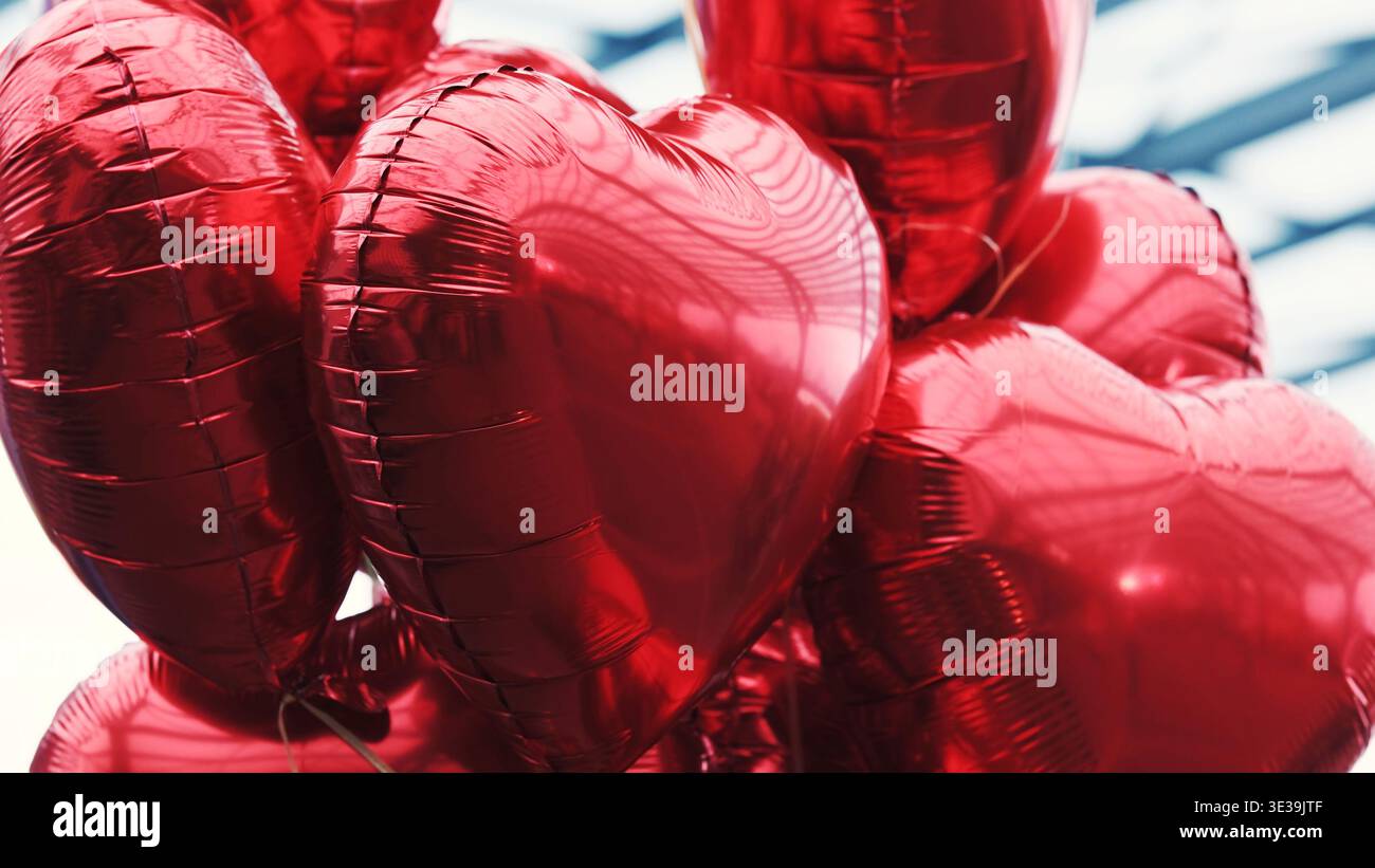 Le palloncini a forma di cuore rosso legati simboleggiano l'amore e il romanticismo Foto Stock