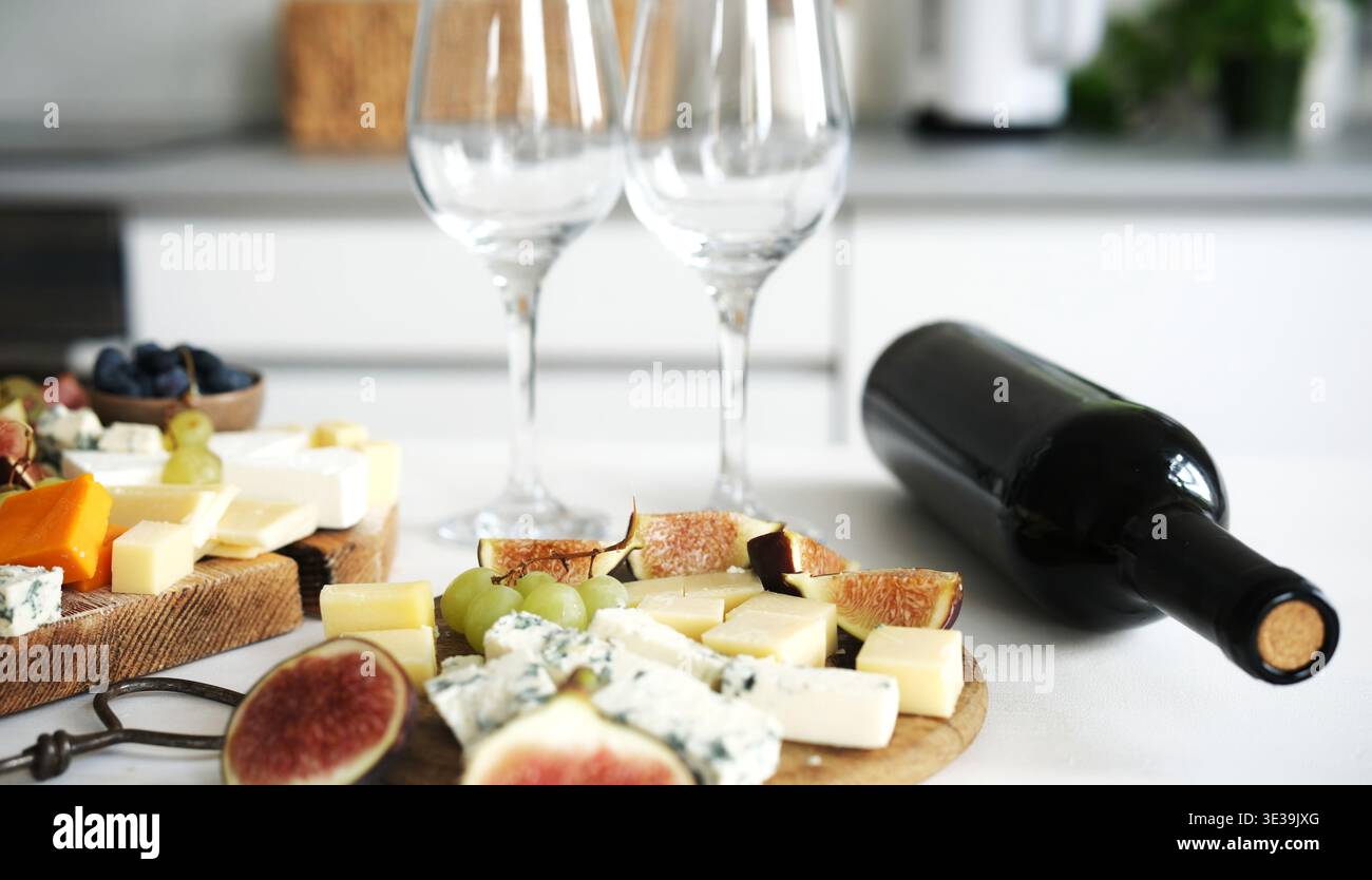 Un tagliere di formaggi con Una bottiglia di vino su Un tavolo crea un piatto appetitoso per Una festa con vino Foto Stock