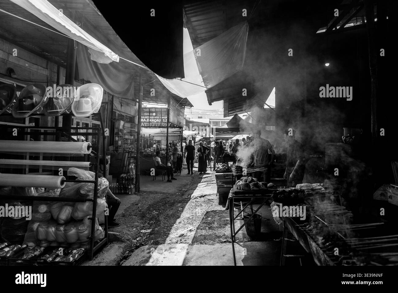 Mercato di strada bianco e nero con venditori, fumo dalle griglie, shopping e vita di tutti i giorni sotto tetti improvvisati. Foto Stock