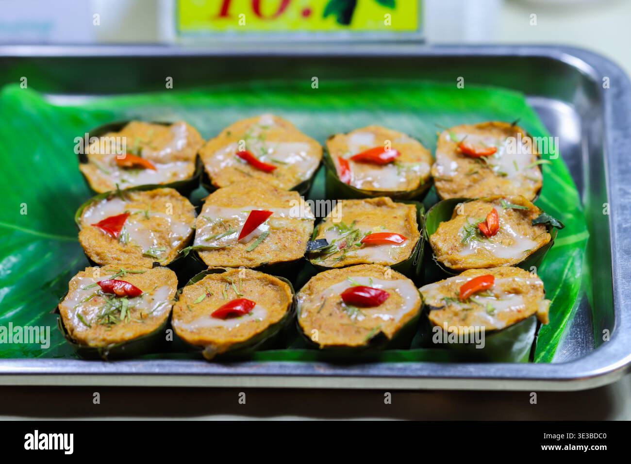 Torta tailandese al curry al vapore in tazze di foglie di banana, che mostra autentico cibo di strada, imballaggi naturali e ricca tradizione culinaria asiatica. Foto Stock