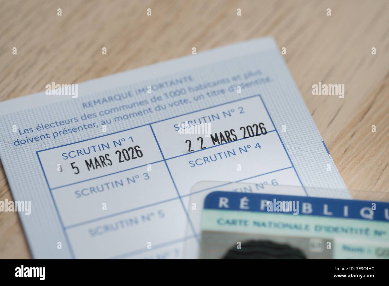 Primo piano di una carta elettorale francese timbrata con le date elettorali del marzo 2026 e di una carta d'identità nazionale parzialmente visibile, che trasmette voto, dovere civico, e Foto Stock