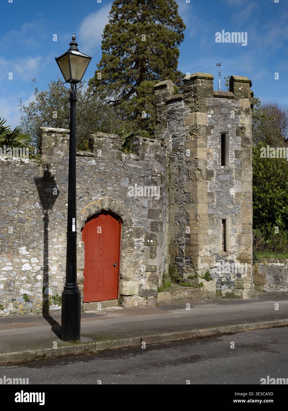 Le mura medievali del castello di Arundel distano dal castello principale che circonda i giardini chiamati "Stumpery" con la sua imponente porta rossa e torre Foto Stock
