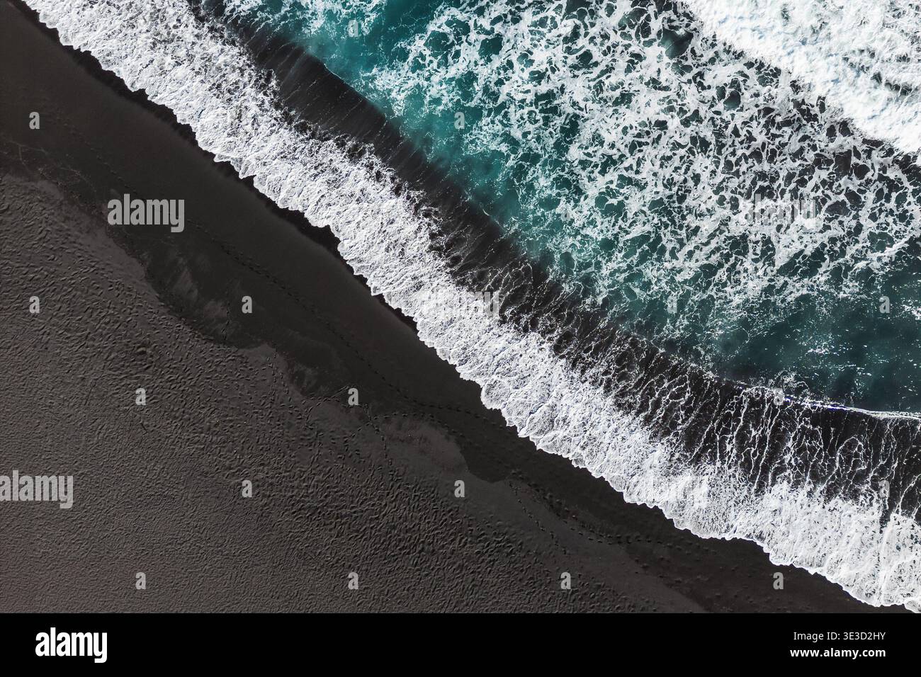 Pile astratte di onde sulla spiaggia di sabbia nera, vista dall'alto verso il basso. Foto Stock