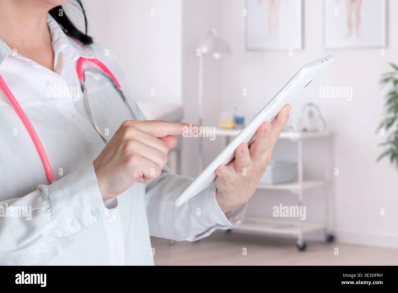 medico che tiene il tablet e interagisce con il touchscreen che rappresenta la tecnologia sanitaria, il software medico e il flusso di lavoro digitale Foto Stock
