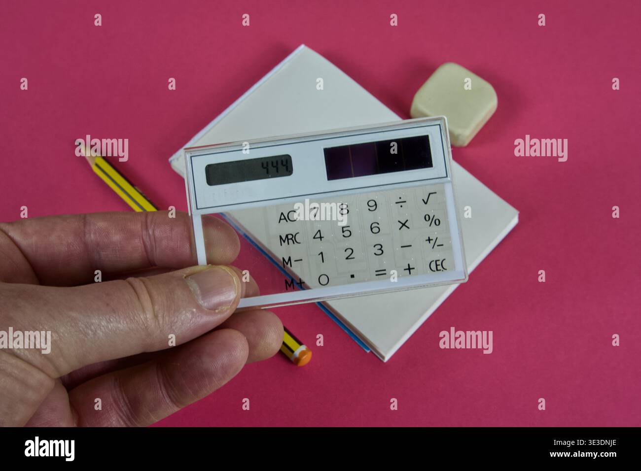 Mano che regge una calcolatrice solare trasparente degli anni '1980 con forniture per ufficio Foto Stock