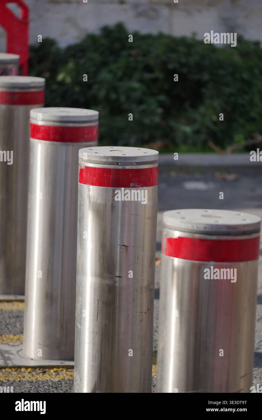 Pali di metallo con le punte rosse si trovano in fila per strada Foto Stock