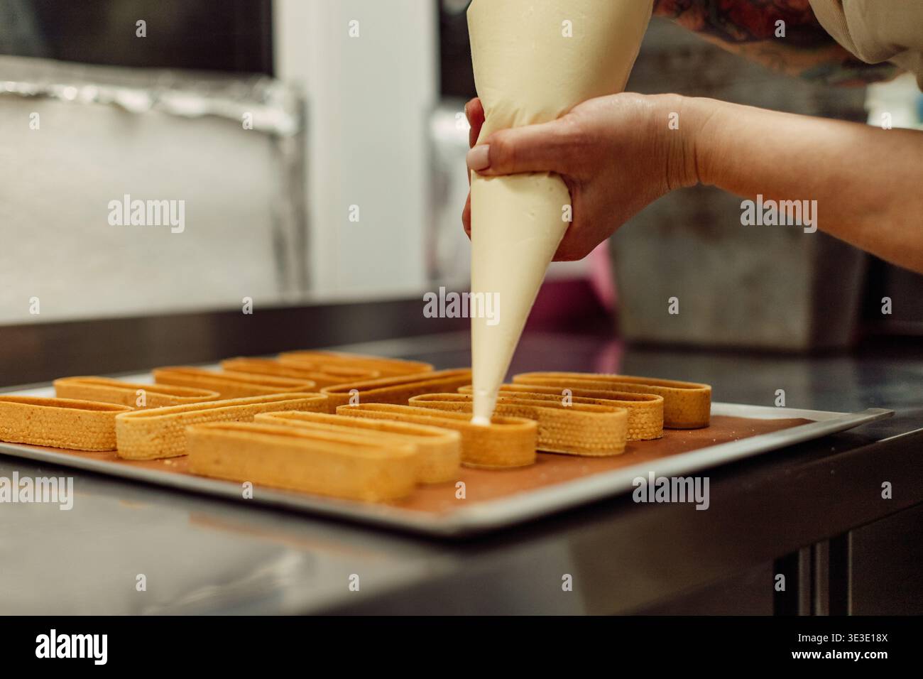 Sacchetto di pasticceria con crema nelle mani di un pasticciere. Processo di preparazione dei dessert. Foto Stock