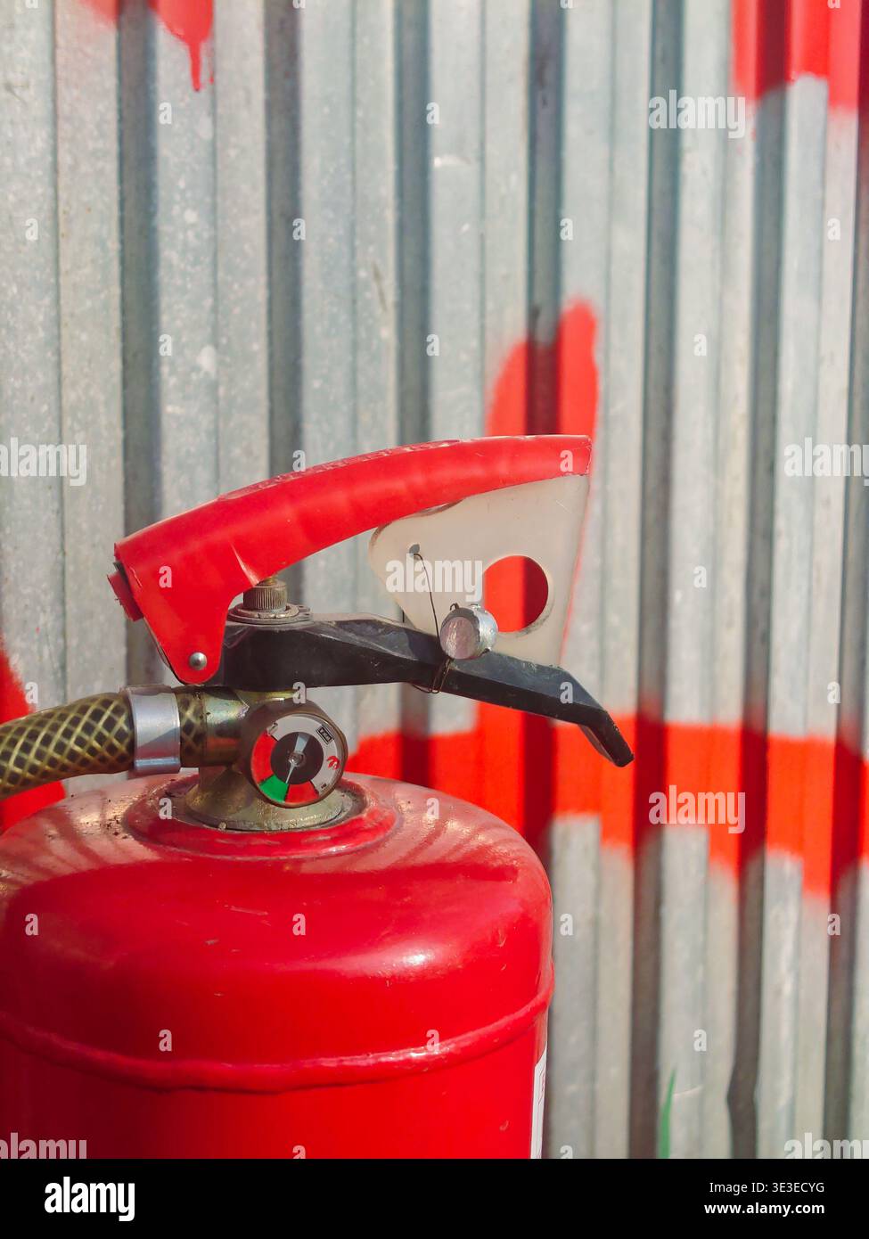 Una macro vista dettagliata del manometro di un estintore rosso, che mostra l'ago nella zona verde sicura. L'immagine include il perno di sicurezza e ha Foto Stock
