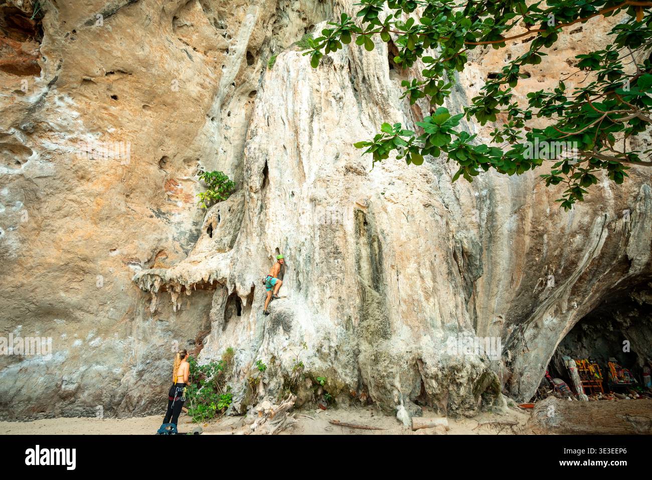 Railay Beach, Thailandia – 23 febbraio 2020: Gli scalatori si arrampicano e si arenano su una scogliera calcarea accanto a una spiaggia sabbiosa. Foto Stock