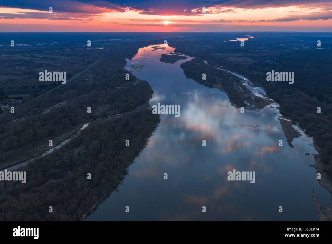 Vista aerea del fiume Vistola vicino a Varsavia mentre si snoda lungo le rive boscose. Le tonalità del cielo rosa e viola si riflettono sull'acqua calma, con isole e vigilia lunga Foto Stock