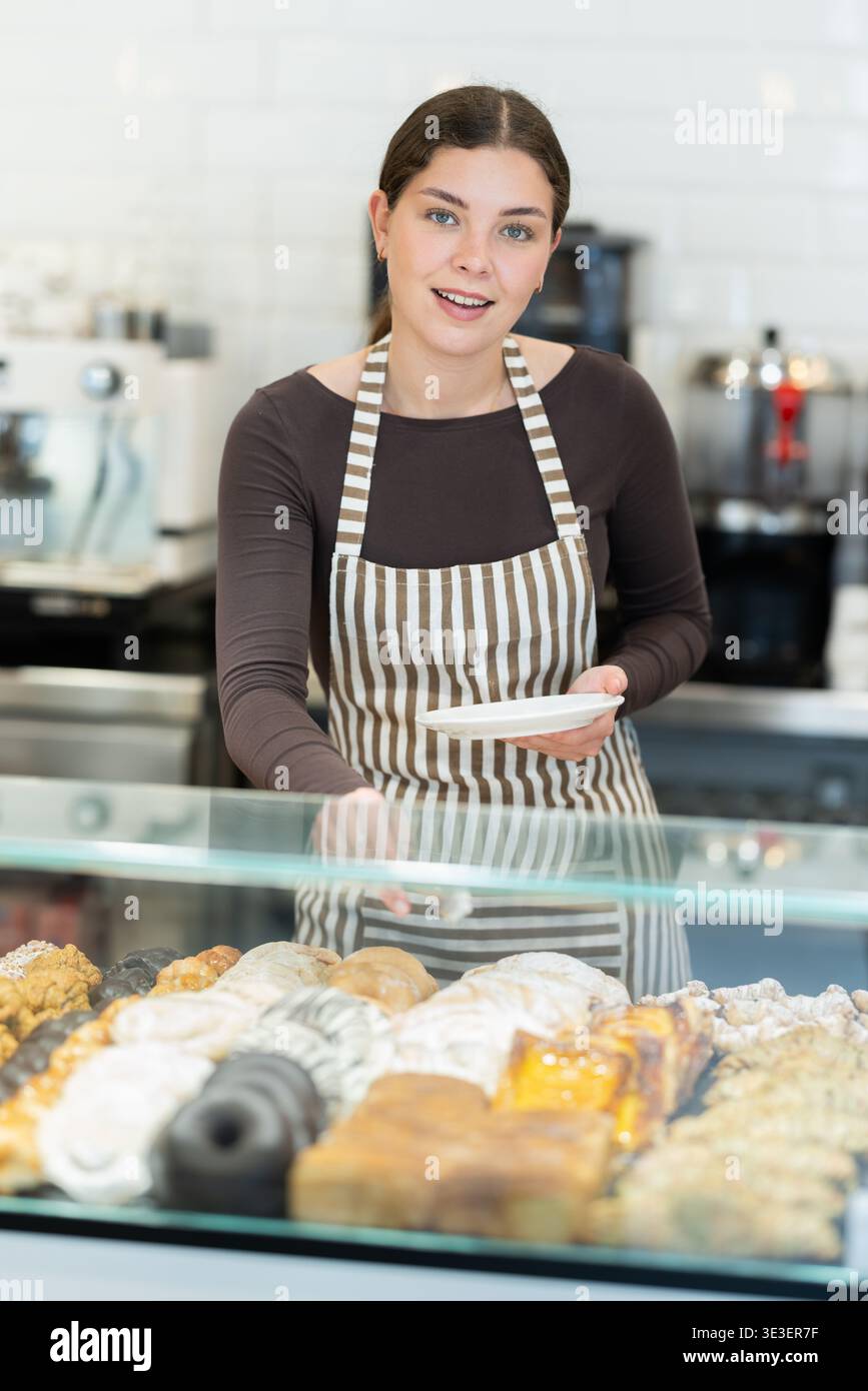 Una ragazza venditrice lavora nel negozio di panetteria della caffetteria Foto Stock