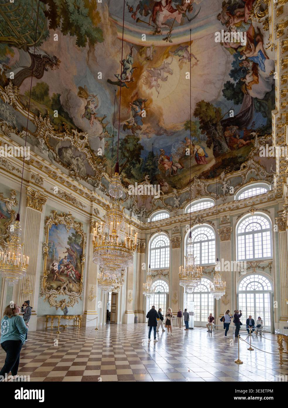 Monaco di Baviera, Germania - 29 marzo 24: Interni decorati del palazzo con lampadari di cristallo, alte finestre ad arco e un affresco sul soffitto riccamente dipinto all'interno della chiesa Foto Stock