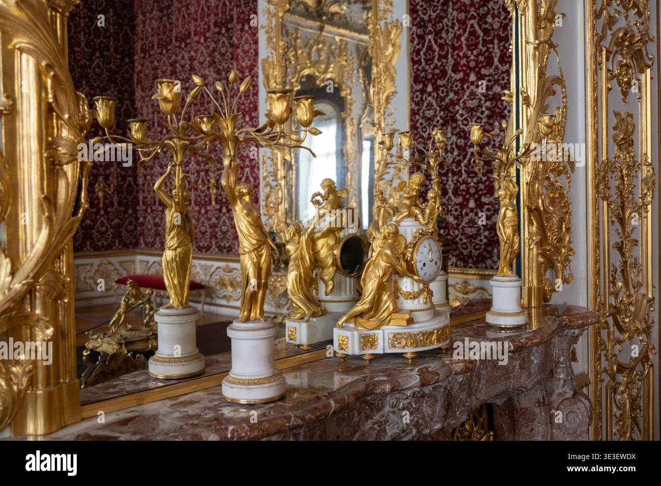 Monaco di Baviera, Germania - 30 marzo 24: Vista ravvicinata di un candelabro dorato e di un orologio decorato che si riflette in una stanza a specchio riccamente decorata presso il Munich Resid Foto Stock