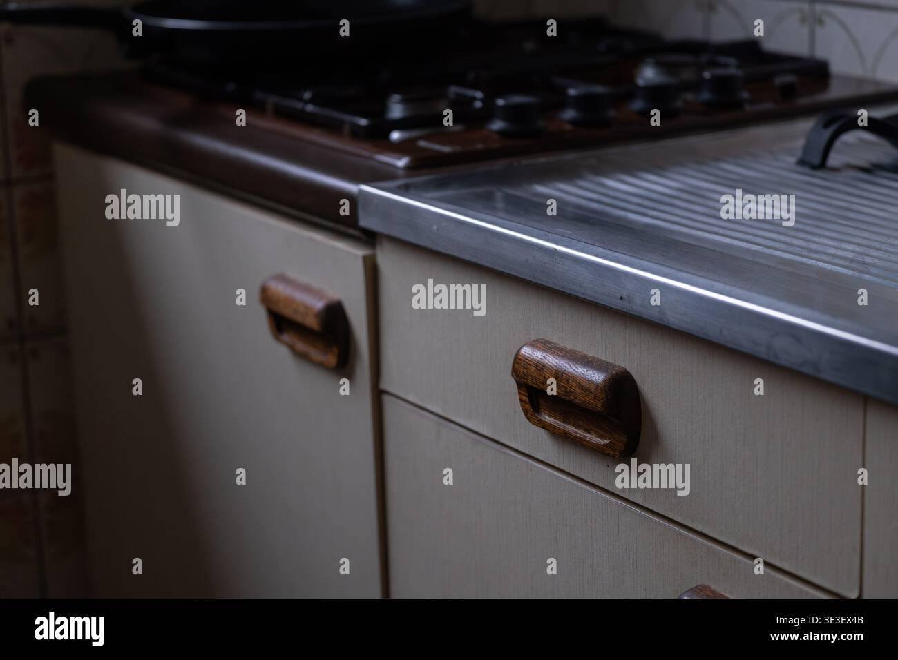 Vecchi armadi da cucina con maniglie in legno e superfici usurate in interni vintage. Autentici dettagli retrò della cucina che mostrano la vita di tutti i giorni e l'imperfec Foto Stock