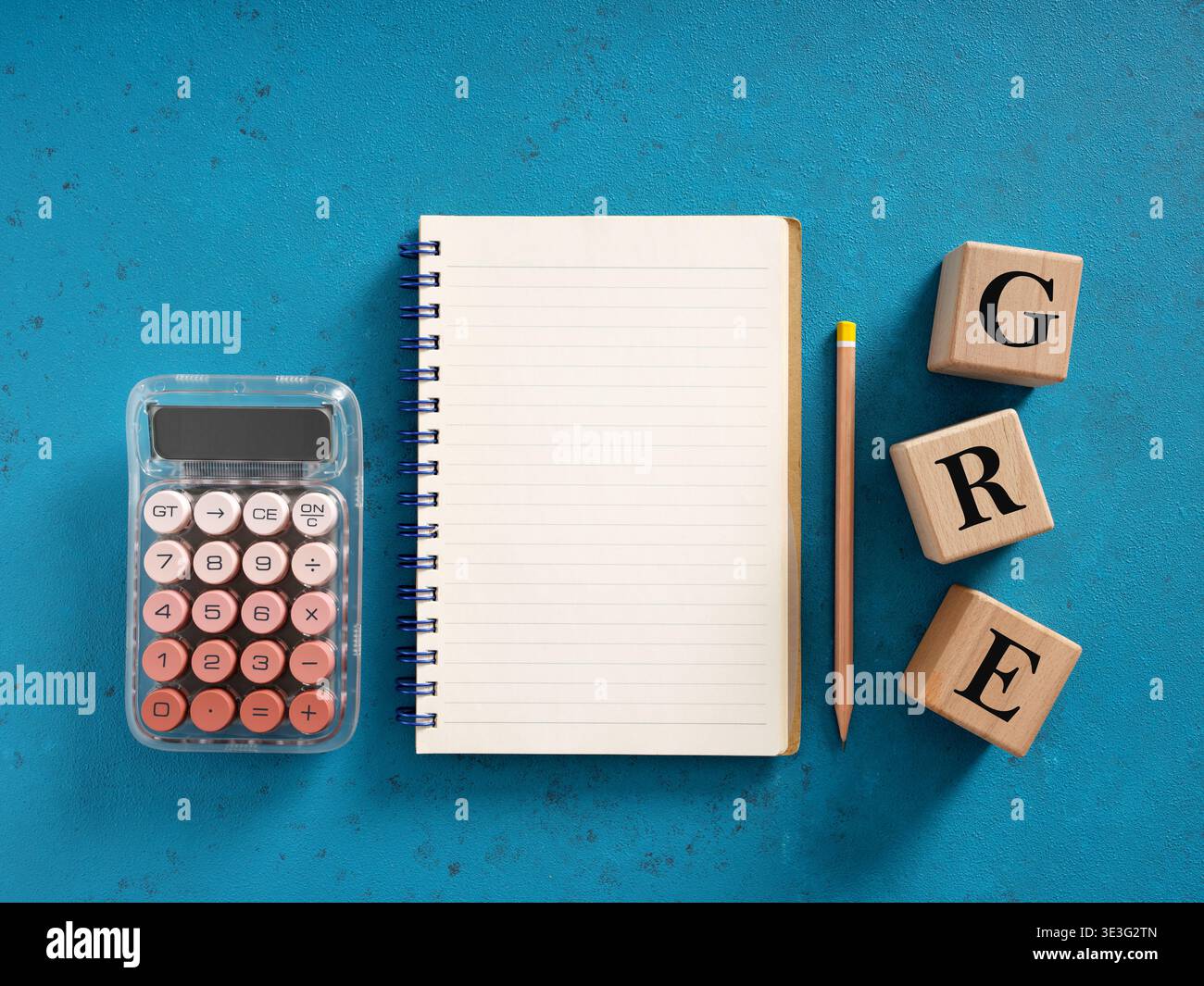 Notebook, calcolatrice e matita su sfondo blu con cubi di legno che compongono la parola GRE, concetto di preparazione all'esame Foto Stock