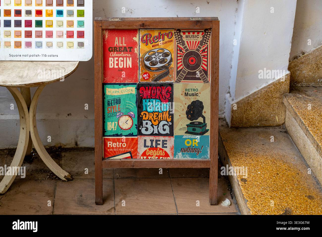 Poster colorati d'epoca adornano un espositore in legno. Il testo include frasi come "tutto grande inizia" e "la vita è grande". Gli adesivi presentano design retrò Foto Stock