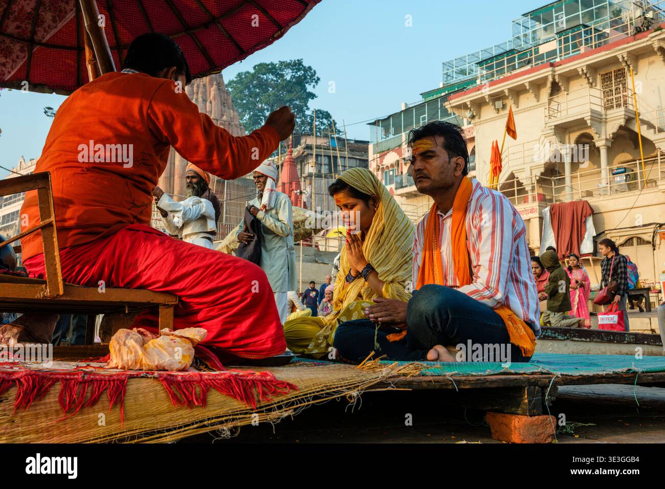 Una coppia prega a occhi chiusi durante una cerimonia guidata da un sacerdote a Dashashwamedh Ghat a Varanasi vicino al fiume Gange. Foto Stock