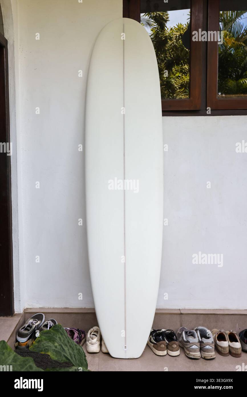 Tavola da surf bianca appoggiata al muro vicino all'ingresso della casa Foto Stock