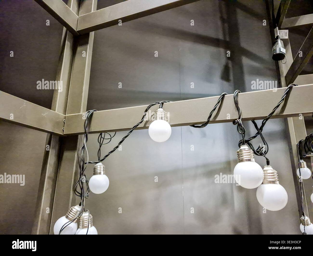 Una serie di luci a LED a globo bianche sono avvolte su una struttura metallica, creando un'illuminazione ambientale per uno spazio interno Foto Stock