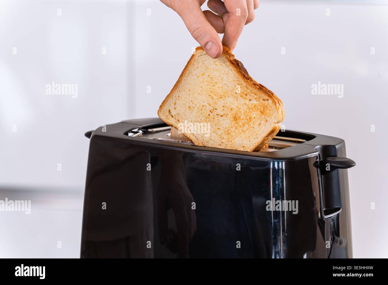 Mettere a mano il pane nel tostapane, inserire e preparare la fetta per tostare, cucinare e preparare la colazione Foto Stock
