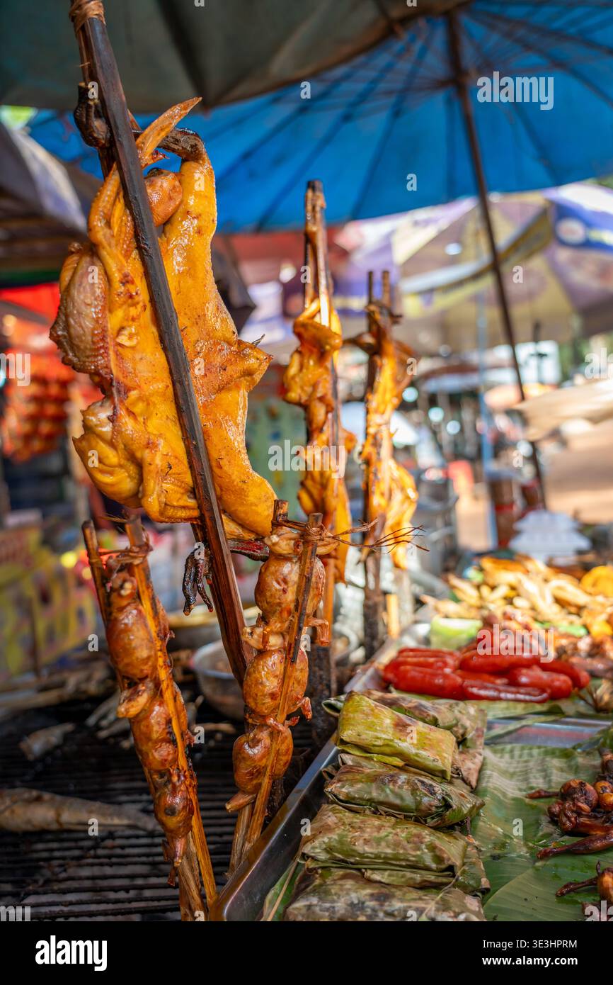 Spiedini di pollo arrosto in una bancarella in un colorato mercato locale, cibo di strada khmer vicino a Siem Reap, Cambogia Foto Stock