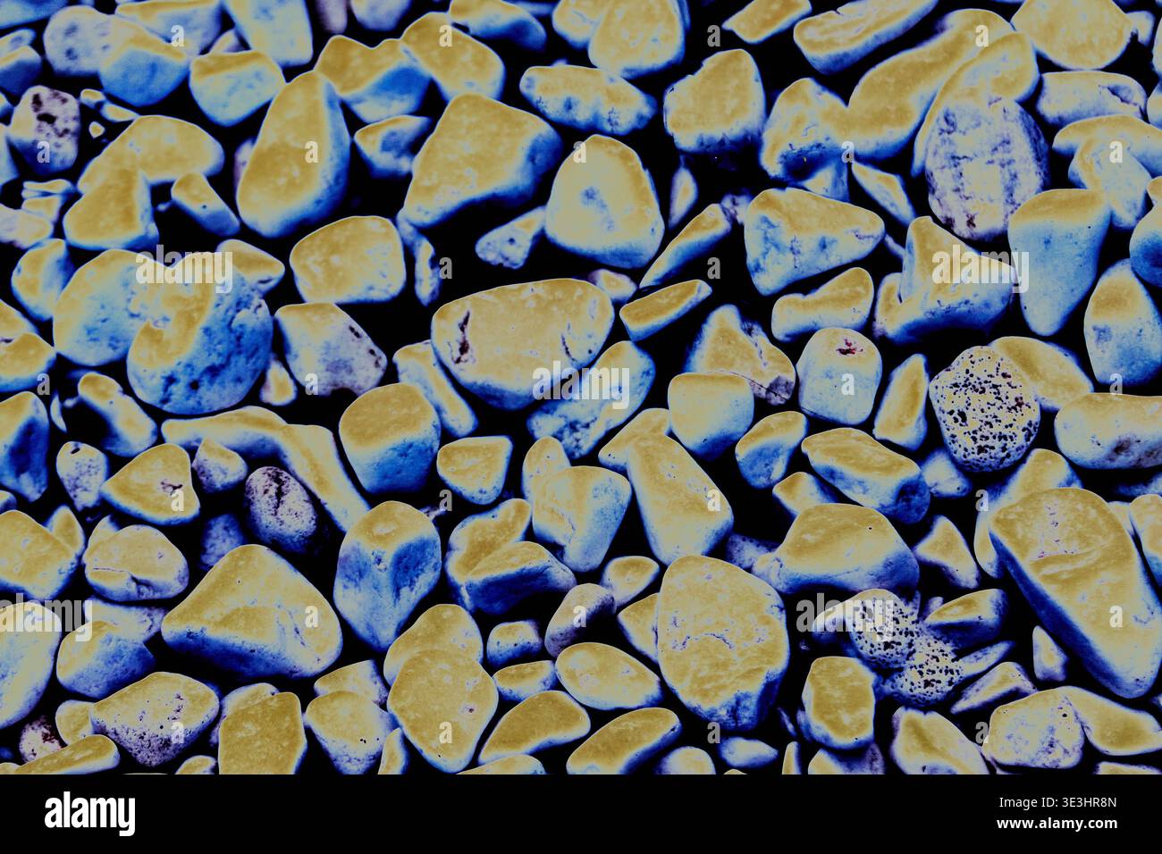 Sfondo in ghiaia con un mix di pietre fluorescenti blu e gialle, che presenta una superficie ruvida con varie forme e dimensioni, ideale per Foto Stock