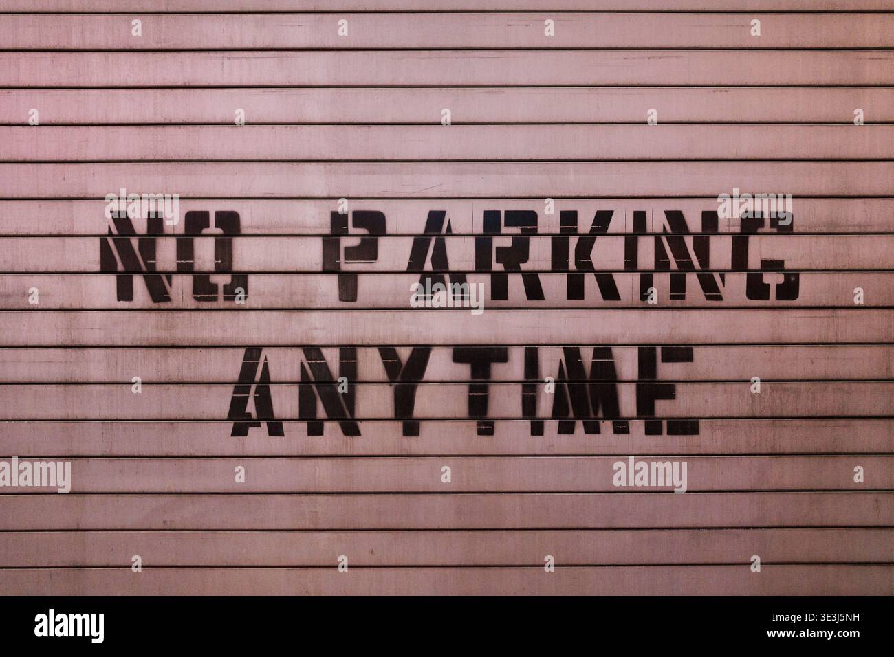 "No Parking Any Time" stenciolato su una superficie metallica ondulata, Manhattan, New York City, 20 marzo 2026. Foto Stock