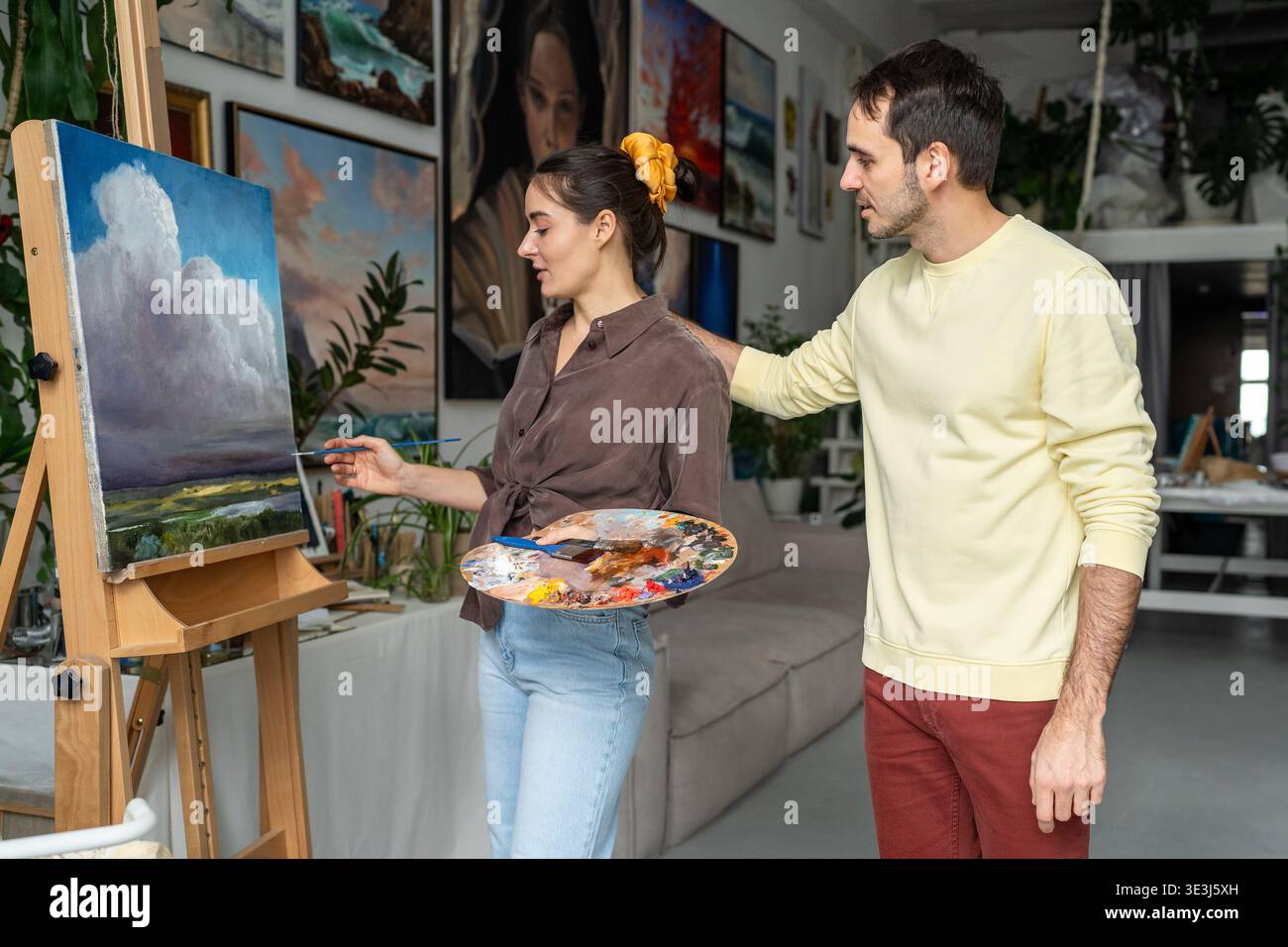 Pittori sorridenti coniugi lavorano sulla pittura. Artista donna felice con marito a casa studio laboratorio Foto Stock