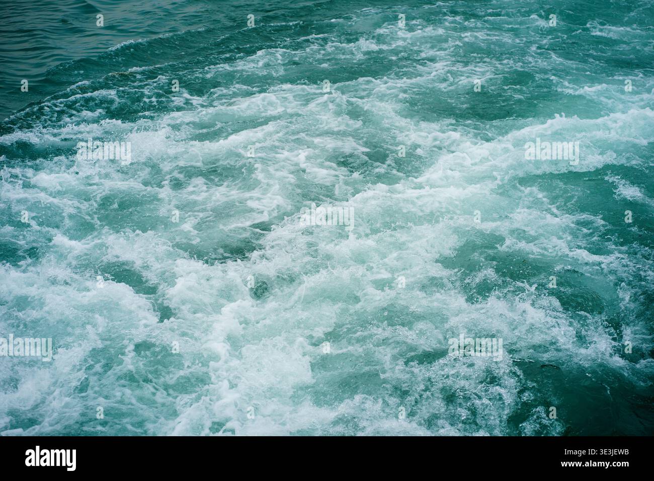 La superficie del lago è caratterizzata da un'acqua turchese e spumeggiante, un movimento dinamico sullo sfondo con onde, bolle e vorticosi motivi acquatici Foto Stock
