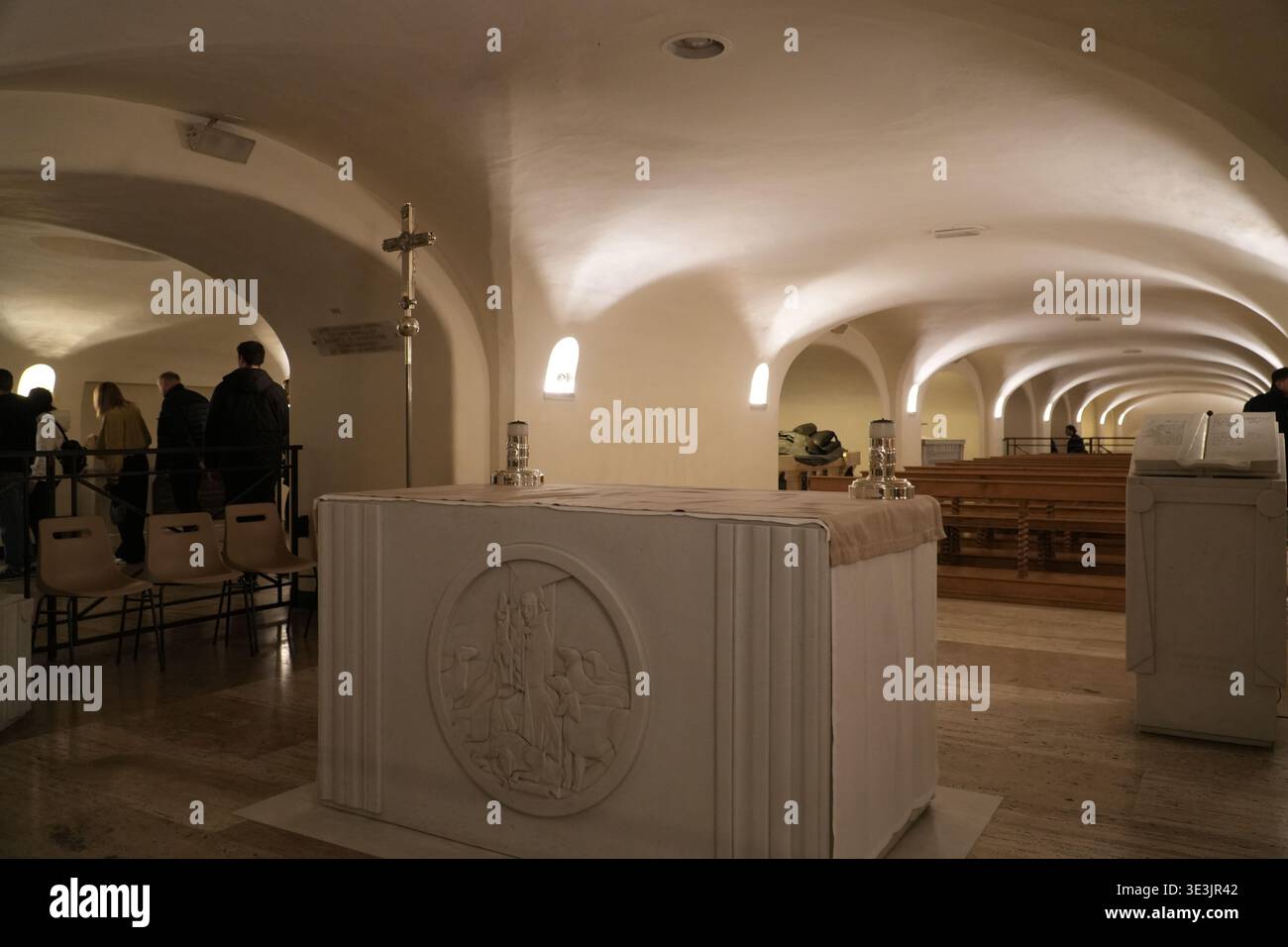 Grotte Vaticane. Piccolo altare con bassorilievo nella Basilica di San Pietro. Turisti che osservano lo spazio sotterraneo sacro, la città del Vaticano Foto Stock
