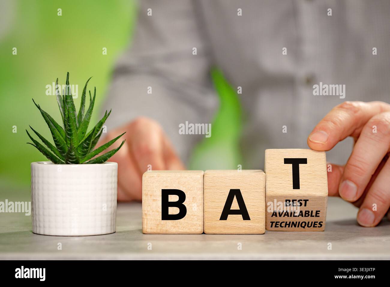 L'uomo d'affari sta trasformando un blocco di legno con il simbolo BAT, migliori tecniche disponibili. Un concetto di business relativo all'ambiente. Prodotti moderni Foto Stock