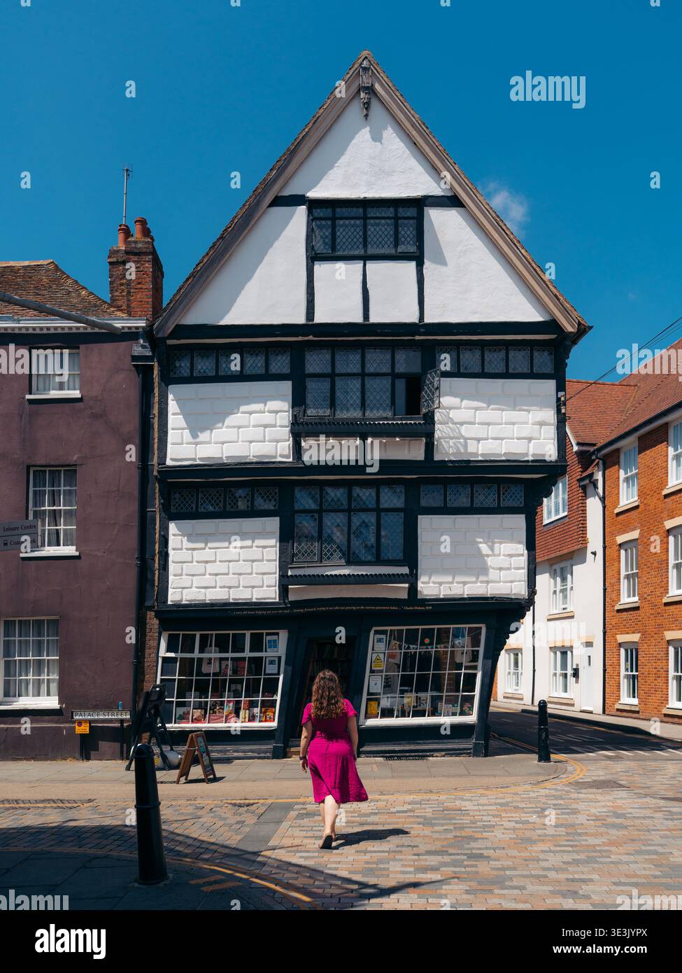 Veduta dell'edificio per metà in legno con facciata bianca e nera che si distingue contro le strutture in mattoni adiacenti, le donne camminano verso di esso, Canterbury, Inghilterra, Foto Stock