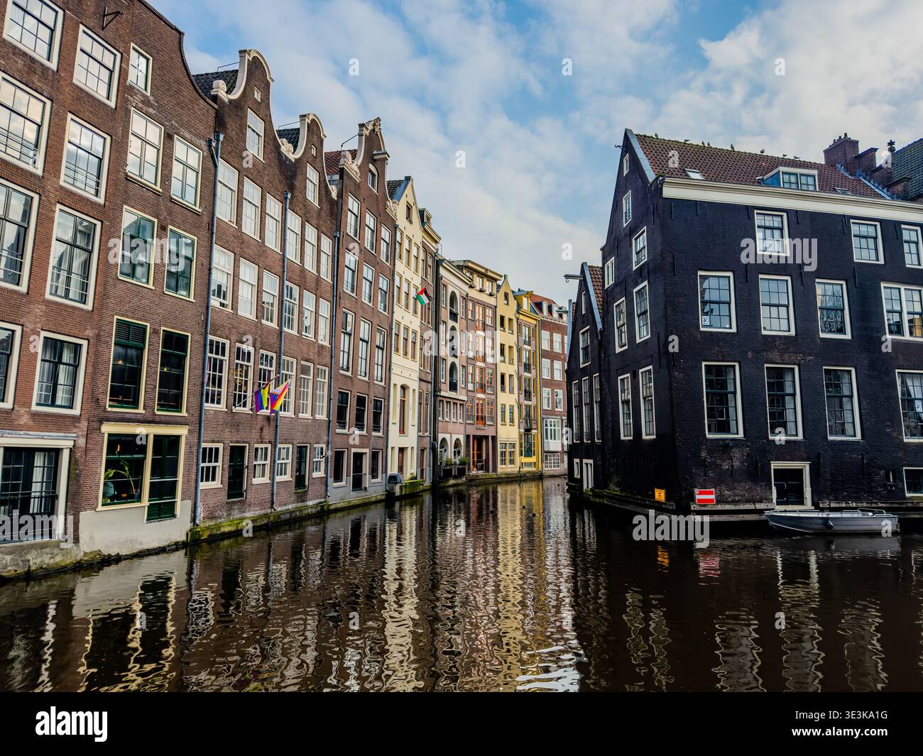 Vista degli edifici storici in mattoni che si specchiano nelle acque tranquille del canale sotto un cielo azzurro e opaco, una tranquilla scena di fascino del vecchio mondo, Amsterdam-centrum, Foto Stock