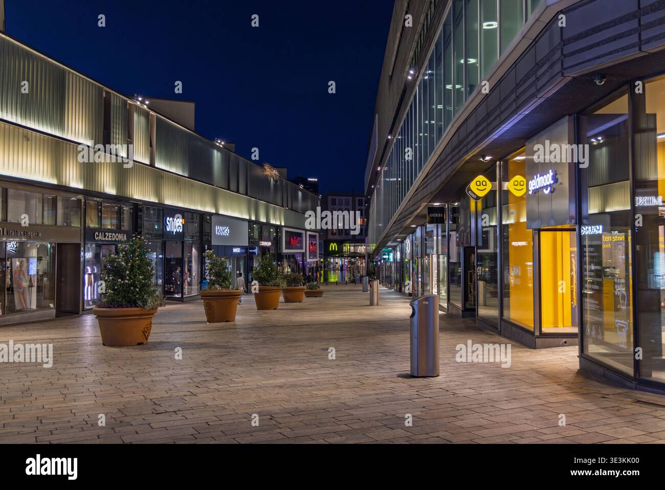Almere, Paesi Bassi. 14 marzo 2026. Empty Shopping Street di notte, moderno quartiere commerciale con vetrine luminose, area pedonale pavimentata e notte L. Foto Stock