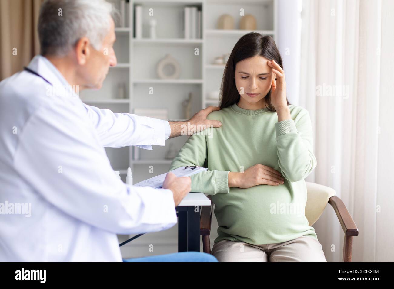 Donna incinta che soffre di mal di testa durante la consultazione medica mentre il medico fornisce supporto Foto Stock