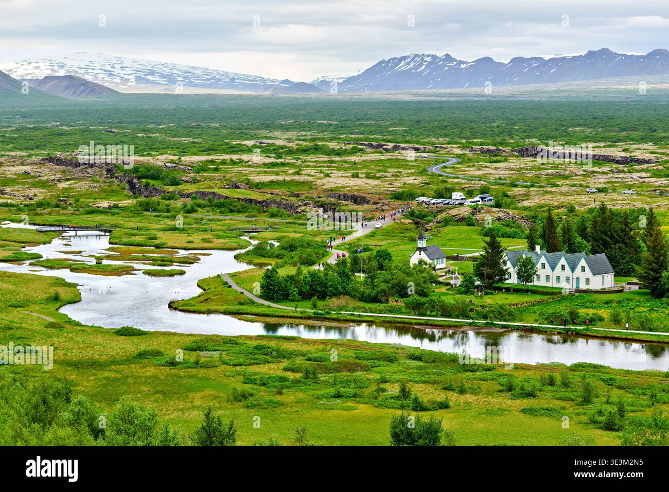 I visitatori camminano lungo i sentieri del Parco Nazionale di Thingvellir. Fiumi e praterie si estendono sotto verdi colline e montagne in lontananza. Foto Stock